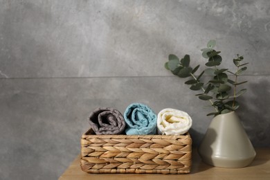 Photo of Waffle towels and vase with branches on wooden dresser near grey wall, space for text