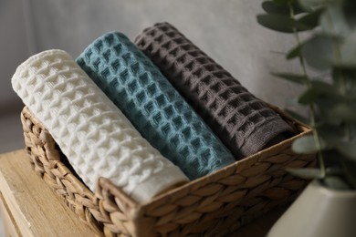 Photo of Waffle towels and vase with branches on wooden dresser near grey wall, closeup
