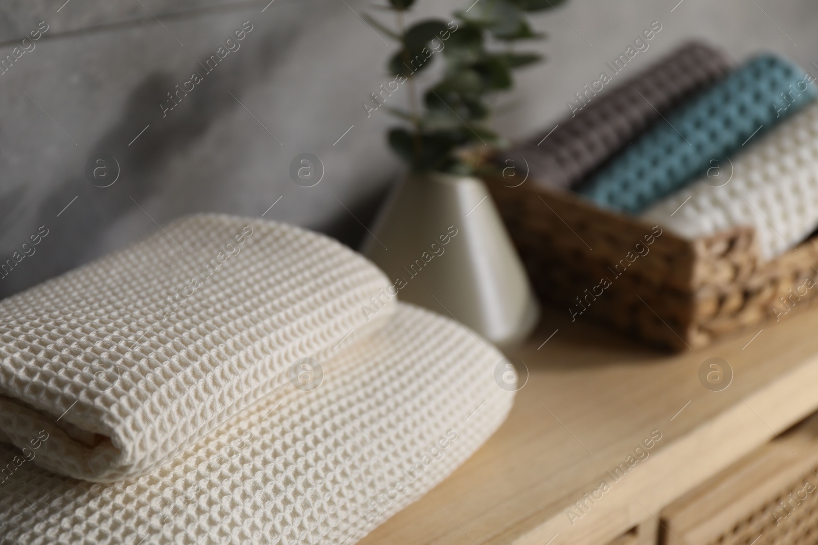 Waffle towels and vase with branches on wooden dresser near grey wall, closeup Photo of Waffle towels and vase with branches on wooden dresser near grey wall, closeup