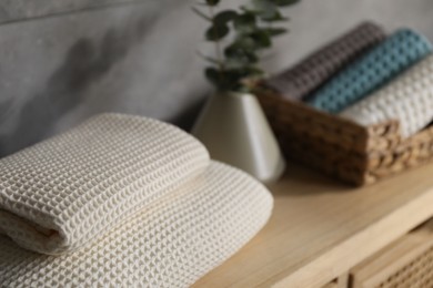 Photo of Waffle towels and vase with branches on wooden dresser near grey wall, closeup