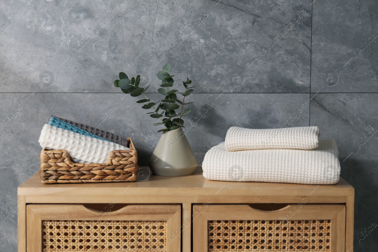 Waffle towels and vase with branches on wooden dresser near grey wall Photo of Waffle towels and vase with branches on wooden dresser near grey wall