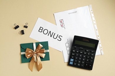 Photo of Card with word Bonus, envelope, binder clips, calculator and checklist on beige background, flat lay