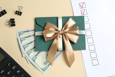 Photo of Money bonus. Envelope, dollar banknotes, binder clips, calculator and checklist on beige background, flat lay