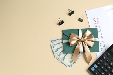 Photo of Money bonus. Envelope, dollars, binder clips, calculator and checklist on beige background, flat lay. Space for text