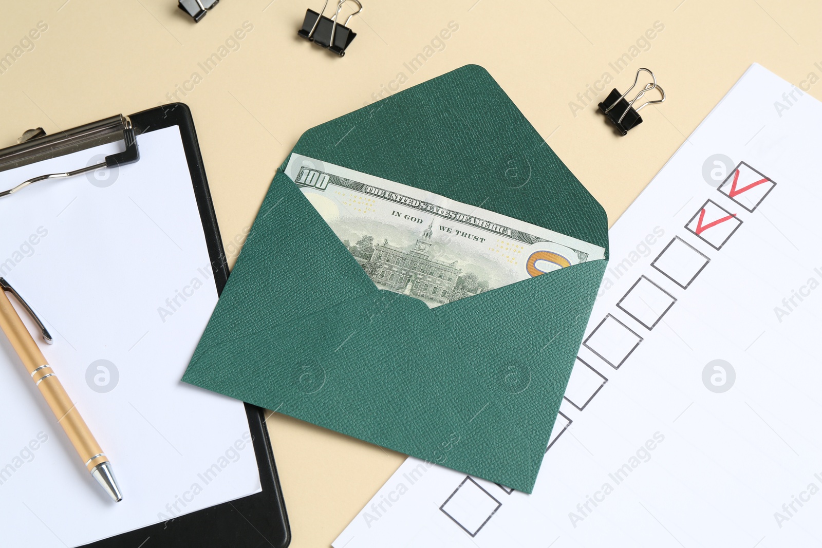 Money bonus. Envelope with dollar banknote, clipboard, checklist and binder clips on beige background, above view Photo of Money bonus. Envelope with dollar banknote, clipboard, checklist and binder clips on beige background, above view