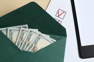 Photo of Money bonus. Envelope with dollar banknotes, clipboard and checklist on beige background, flat lay