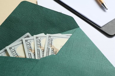 Photo of Money bonus. Envelope with dollar banknotes and clipboard on beige background, closeup