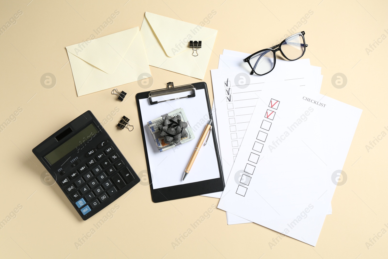Money bonus. Dollar banknotes with bow, stationery, calculator, glasses and checklists on beige background, flat lay Photo of Money bonus. Dollar banknotes with bow, stationery, calculator, glasses and checklists on beige background, flat lay