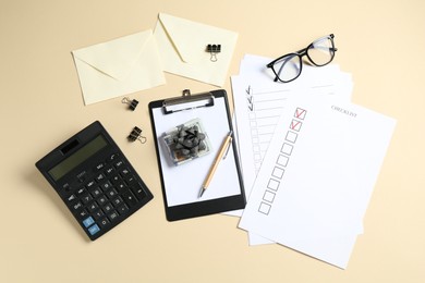 Photo of Money bonus. Dollar banknotes with bow, stationery, calculator, glasses and checklists on beige background, flat lay
