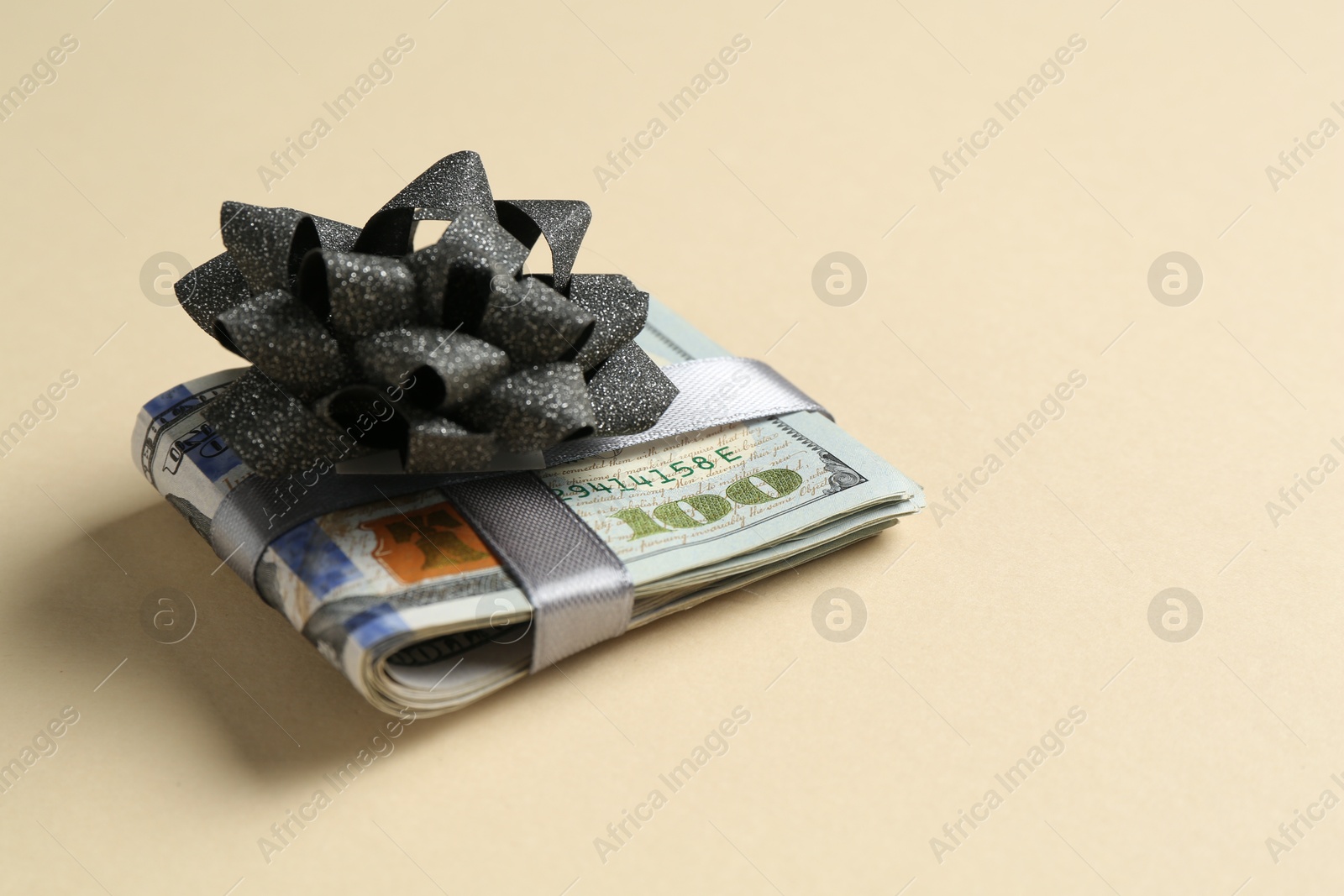 Money bonus. Dollar banknotes with bow on beige background, closeup. Space for text Photo of Money bonus. Dollar banknotes with bow on beige background, closeup. Space for text