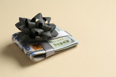 Photo of Money bonus. Dollar banknotes with bow on beige background, closeup. Space for text