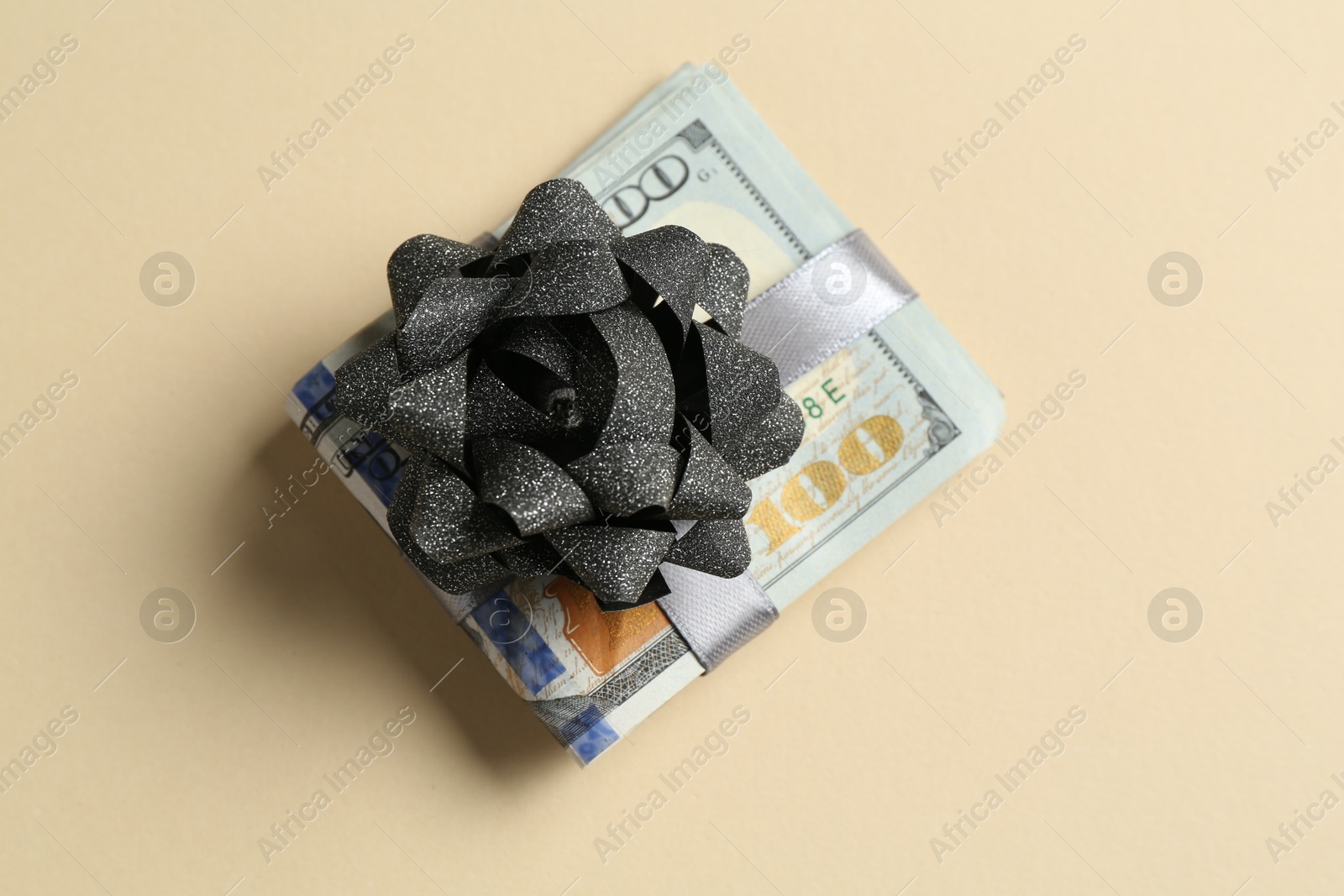 Money bonus. Dollar banknotes with bow on beige background, top view Photo of Money bonus. Dollar banknotes with bow on beige background, top view