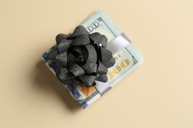 Photo of Money bonus. Dollar banknotes with bow on beige background, top view