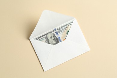 Photo of Money bonus. Envelope with dollar banknote on beige background, top view