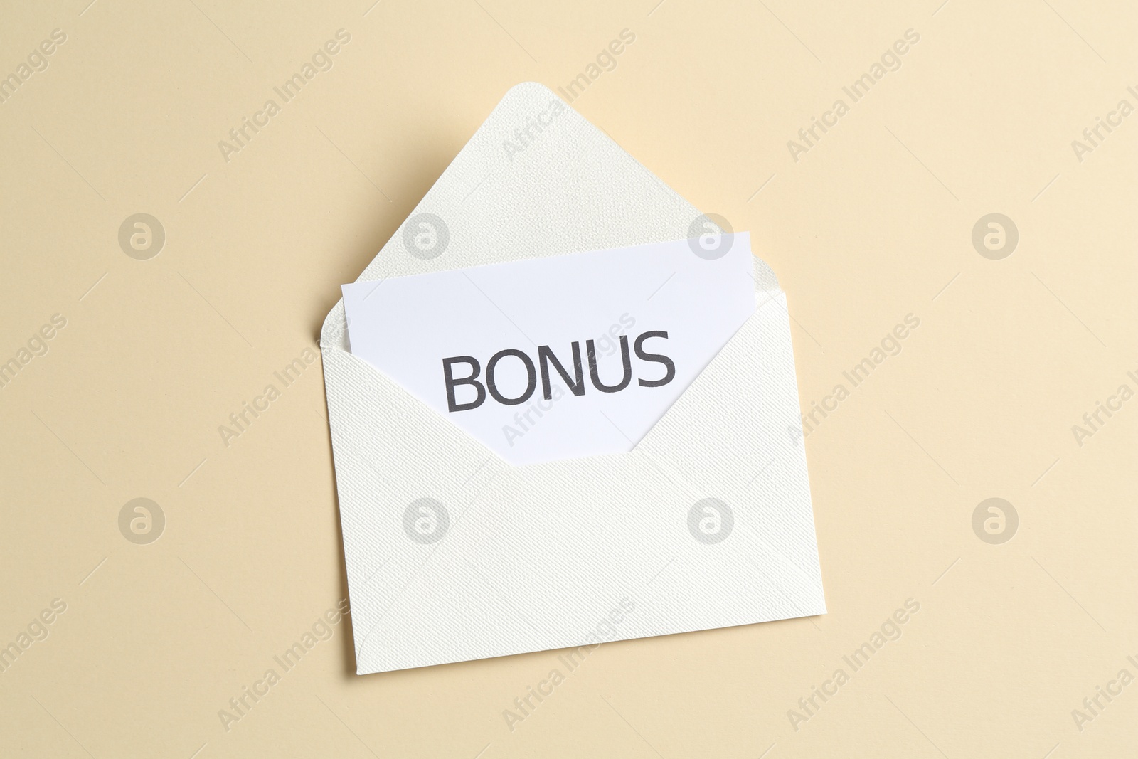 Card with word Bonus and envelope on beige background, top view Photo of Card with word Bonus and envelope on beige background, top view