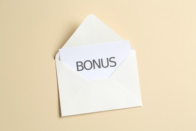 Photo of Card with word Bonus and envelope on beige background, top view