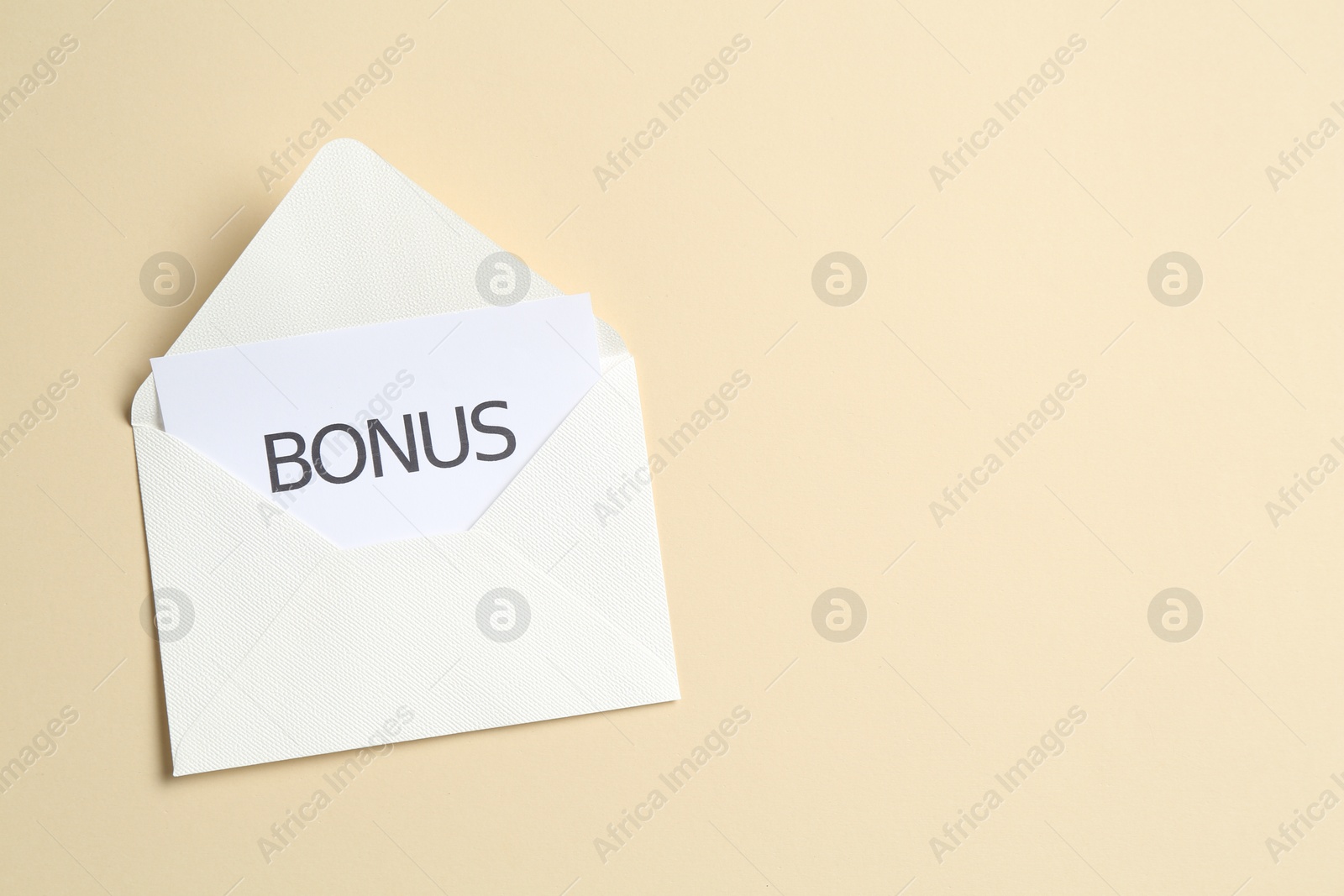 Card with word Bonus and envelope on beige background, top view. Space for text Photo of Card with word Bonus and envelope on beige background, top view. Space for text