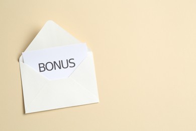 Photo of Card with word Bonus and envelope on beige background, top view. Space for text