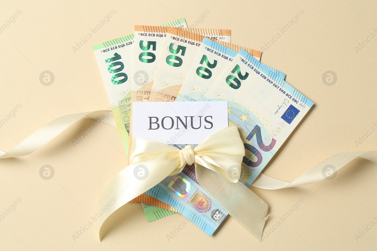 Card with word Bonus, euro banknotes and bow on beige background, flat lay Photo of Card with word Bonus, euro banknotes and bow on beige background, flat lay