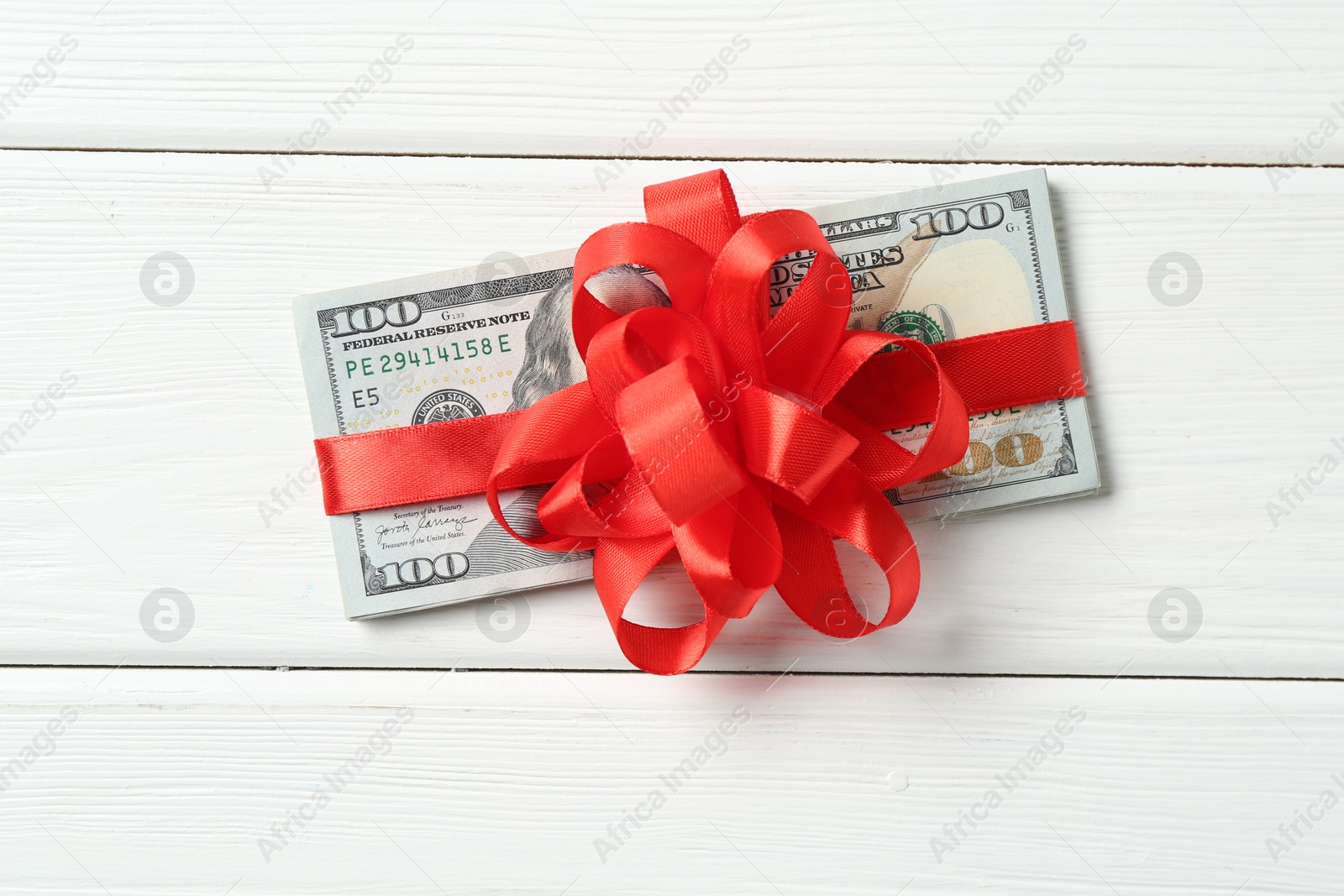 Money bonus. Dollar banknotes with bow on white wooden table, top view Photo of Money bonus. Dollar banknotes with bow on white wooden table, top view