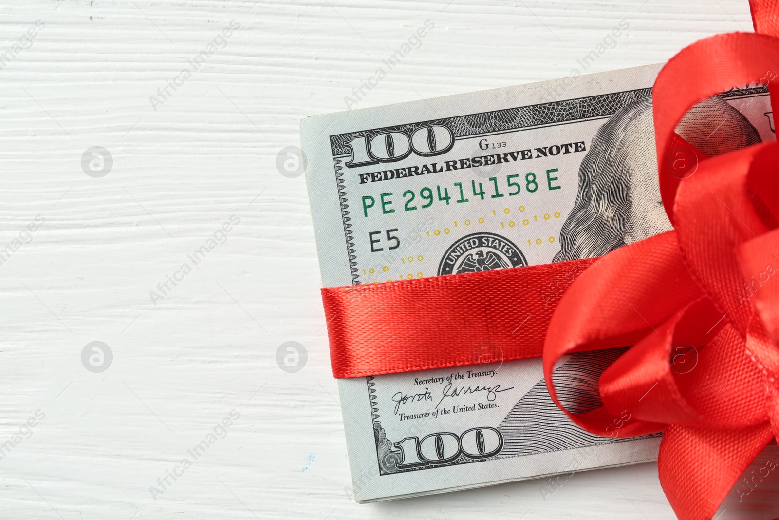 Money bonus. Dollar banknotes with bow on white wooden table, top view. Space for text Photo of Money bonus. Dollar banknotes with bow on white wooden table, top view. Space for text