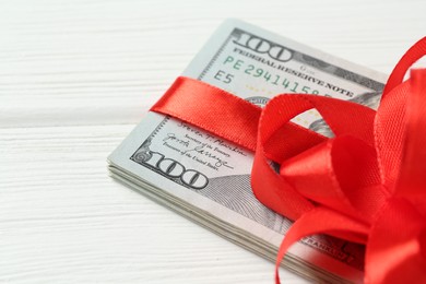 Photo of Money bonus. Dollar banknotes with bow on white wooden table, closeup