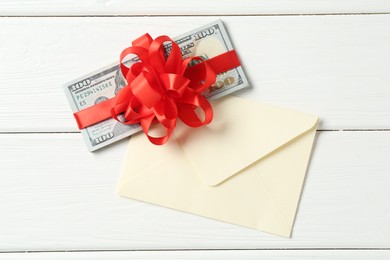 Photo of Money bonus. Dollar banknotes with bow and envelope on white wooden table, flat lay