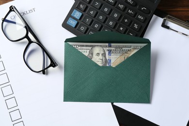 Photo of Money bonus. Envelope with dollar banknote, clipboard, checklist, glasses and calculator on table, flat lay