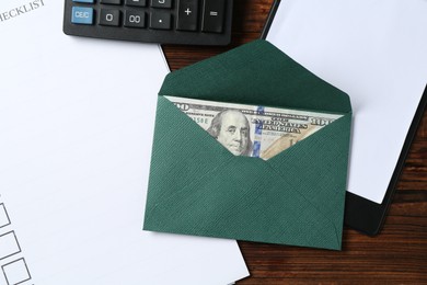 Photo of Money bonus. Envelope with dollar banknote, clipboard, checklist and calculator on wooden table, flat lay