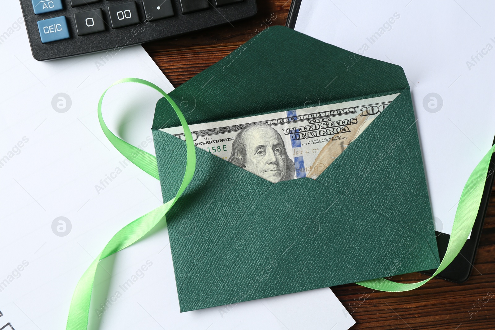 Money bonus. Envelope with dollar banknote, clipboard, ribbon and calculator on wooden table, flat lay Photo of Money bonus. Envelope with dollar banknote, clipboard, ribbon and calculator on wooden table, flat lay
