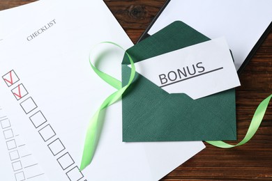 Photo of Card with word Bonus, envelope, ribbon, checklist and clipboard on wooden table, flat lay