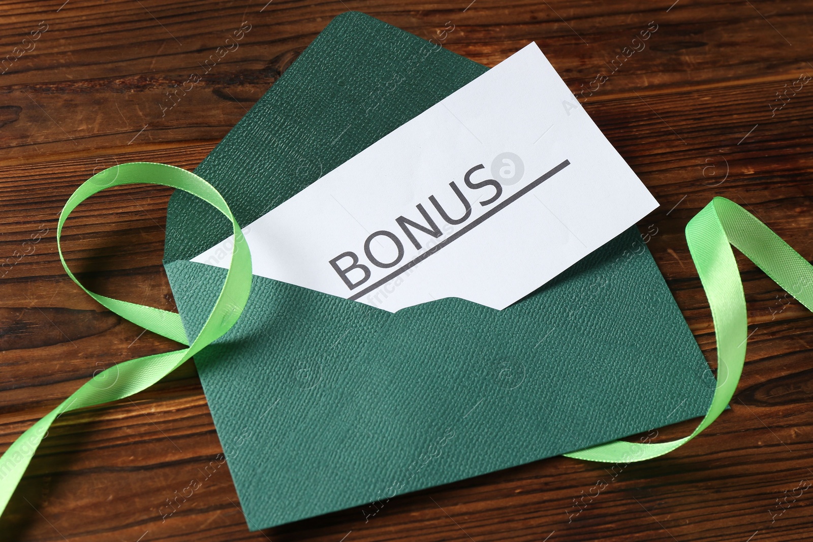 Card with word Bonus, envelope and ribbon on wooden table, above view Photo of Card with word Bonus, envelope and ribbon on wooden table, above view