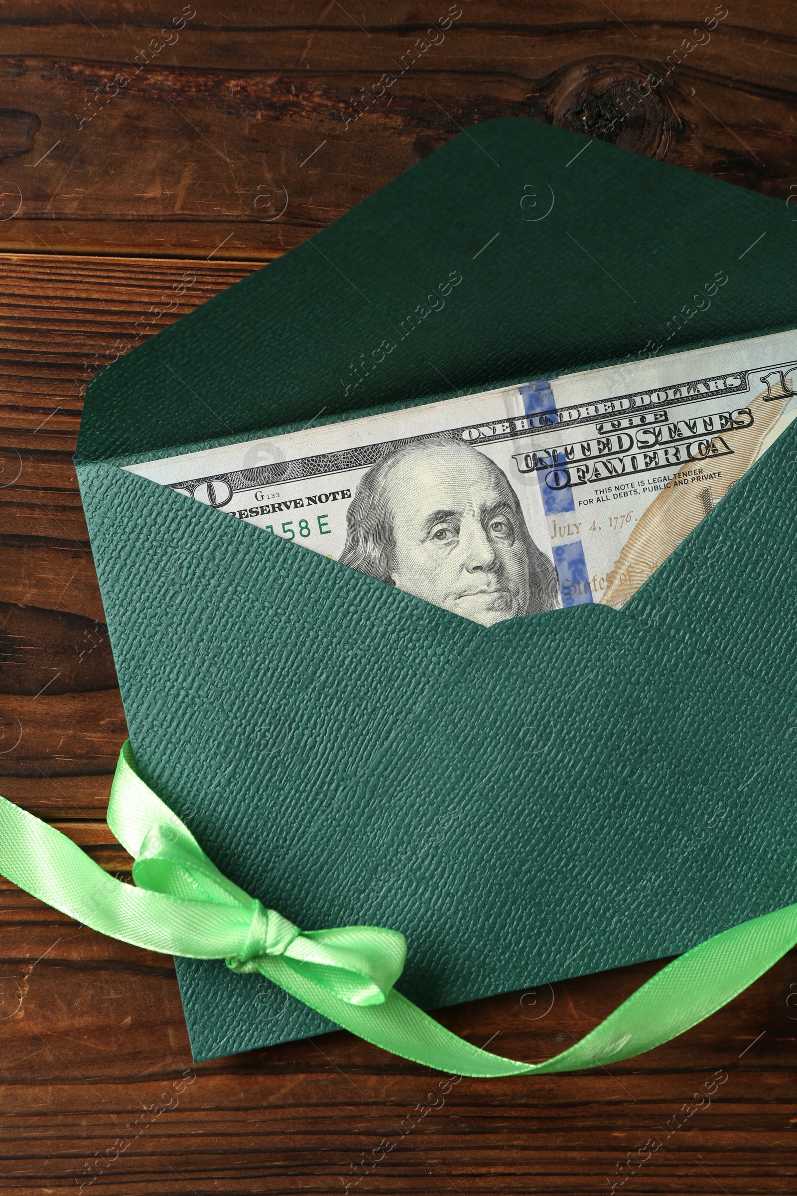 Money bonus. Envelope with dollar banknote and ribbon on wooden table, top view Photo of Money bonus. Envelope with dollar banknote and ribbon on wooden table, top view