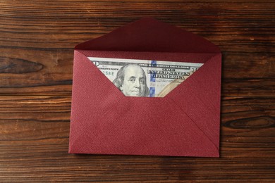 Photo of Money bonus. Envelope with dollar banknote on wooden table, top view