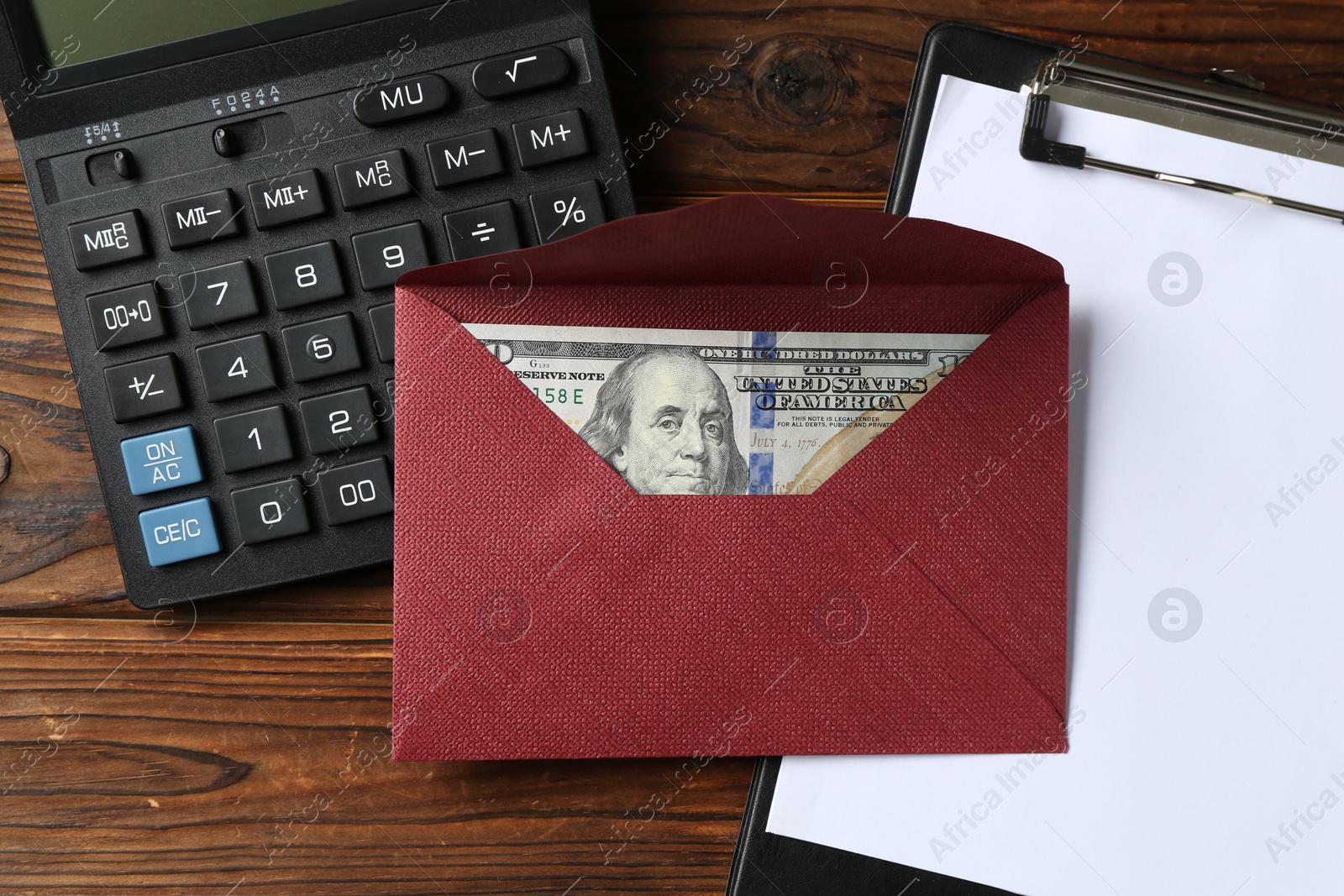 Money bonus. Envelope with dollar banknote, clipboard and calculator on wooden table, flat lay Photo of Money bonus. Envelope with dollar banknote, clipboard and calculator on wooden table, flat lay