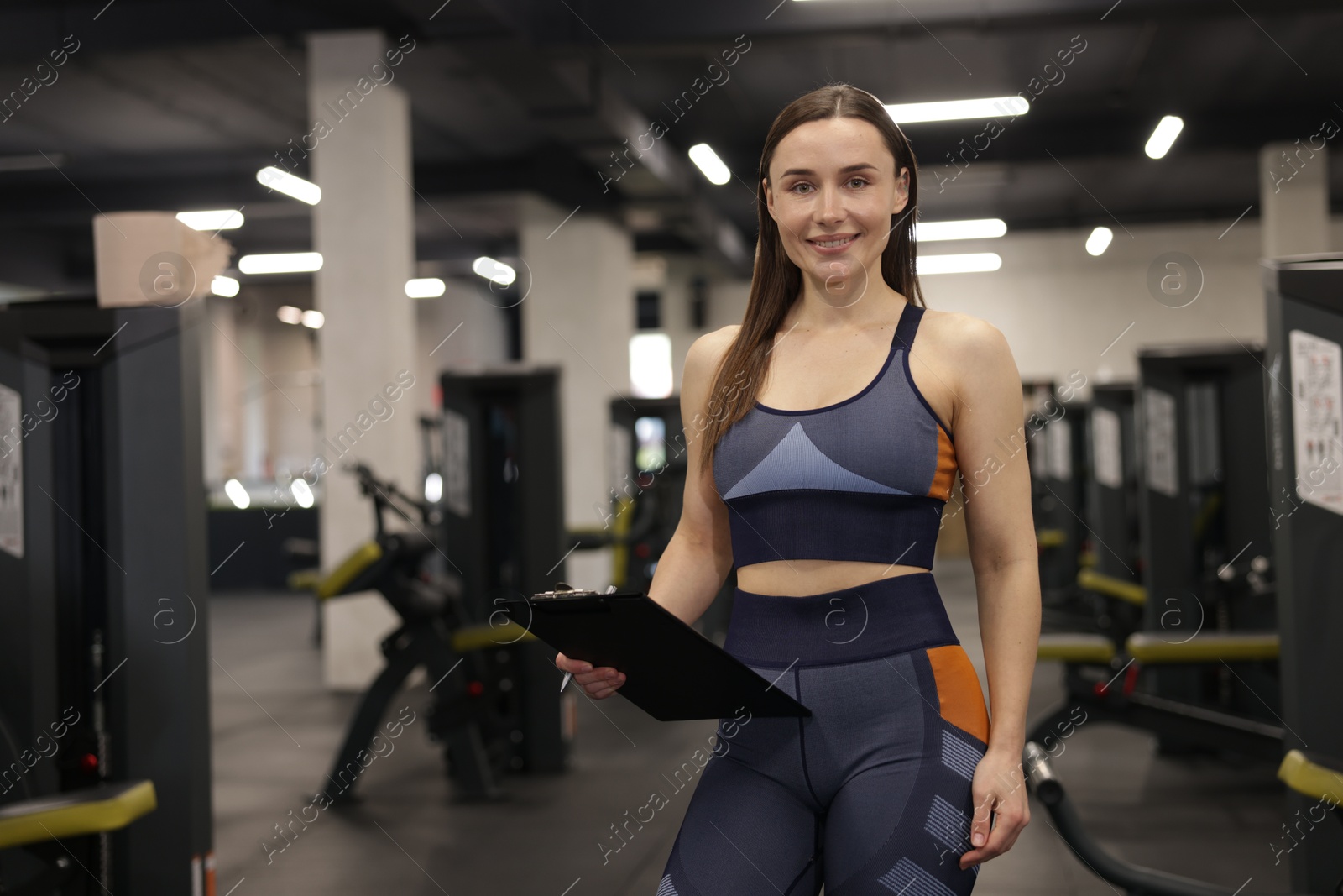 Professional personal trainer with clipboard in gym. Space for text Photo of Professional personal trainer with clipboard in gym. Space for text