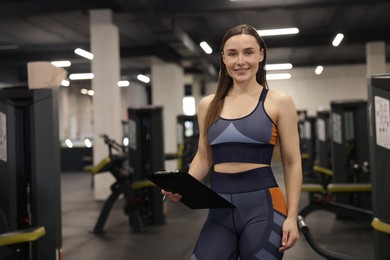 Photo of Professional personal trainer with clipboard in gym. Space for text