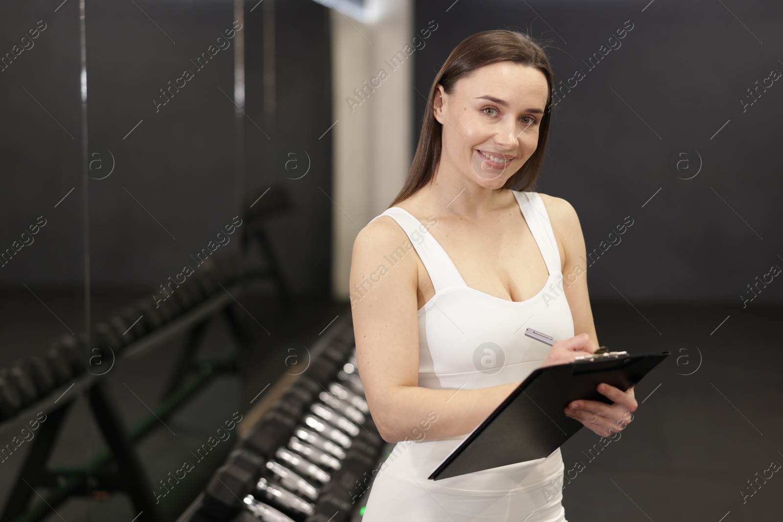 Photo of Professional personal trainer with clipboard in gym. Space for text