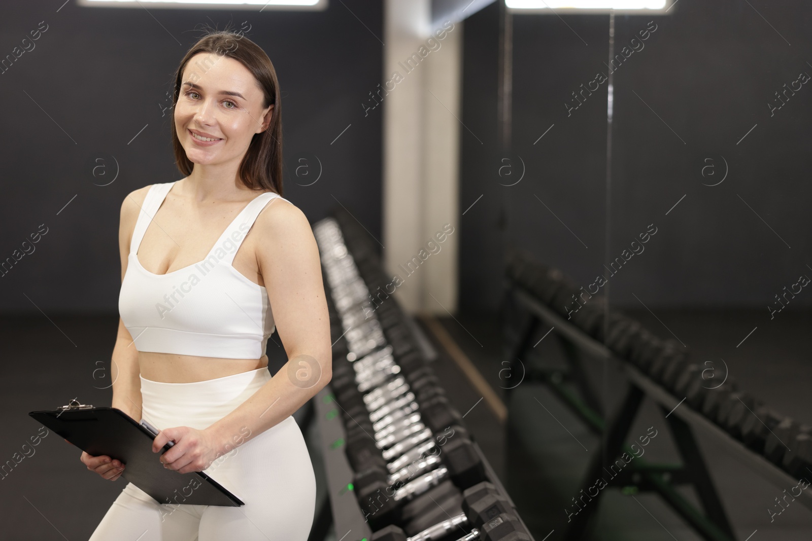 Professional personal trainer with clipboard in gym. Space for text Photo of Professional personal trainer with clipboard in gym. Space for text