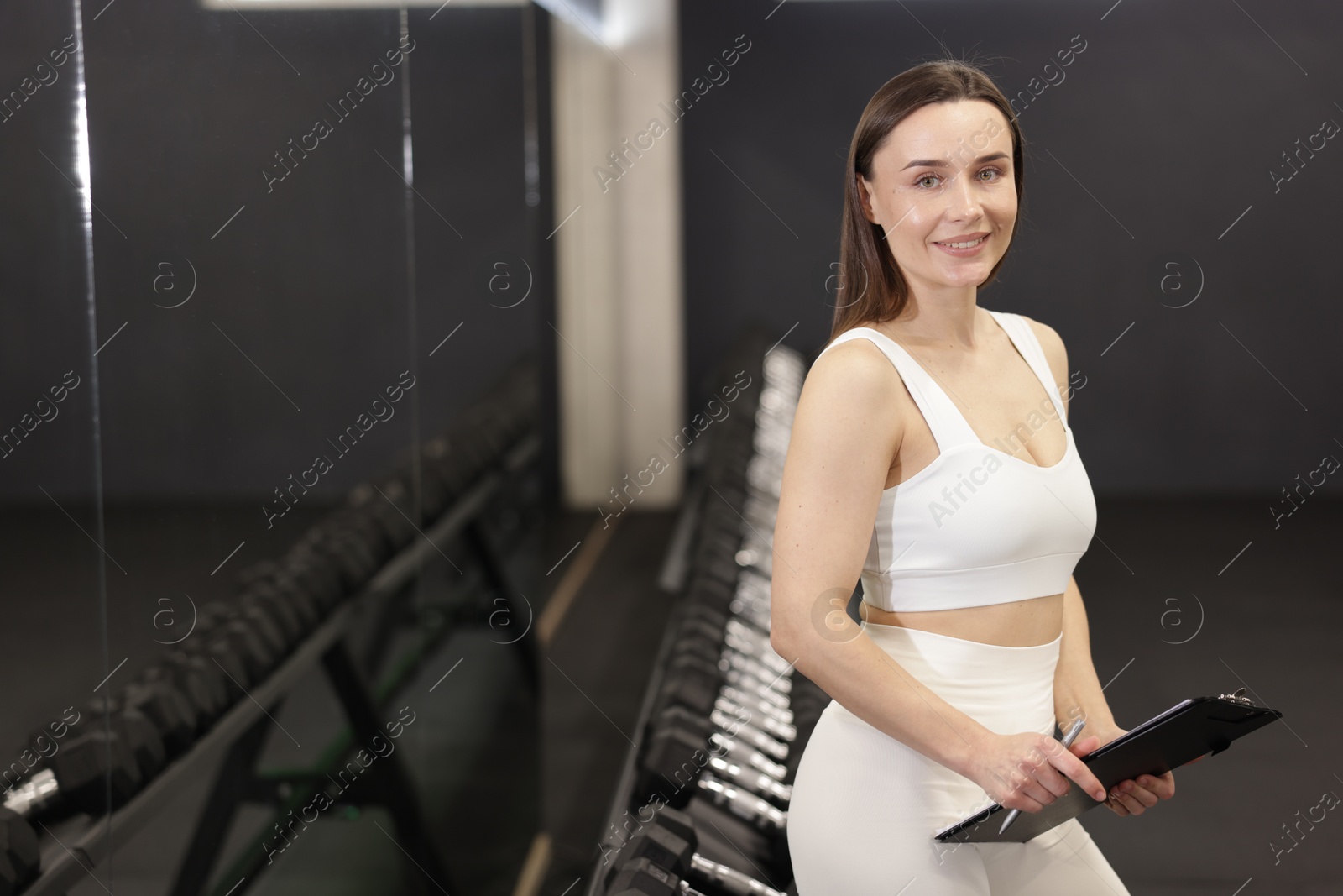 Photo of Professional personal trainer with clipboard in gym. Space for text