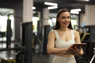 Photo of Personal trainer with tablet in sport center. Space for text
