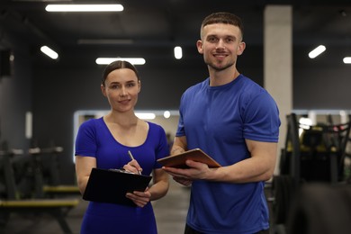 Photo of Personal trainers with clipboard and tablet in gym