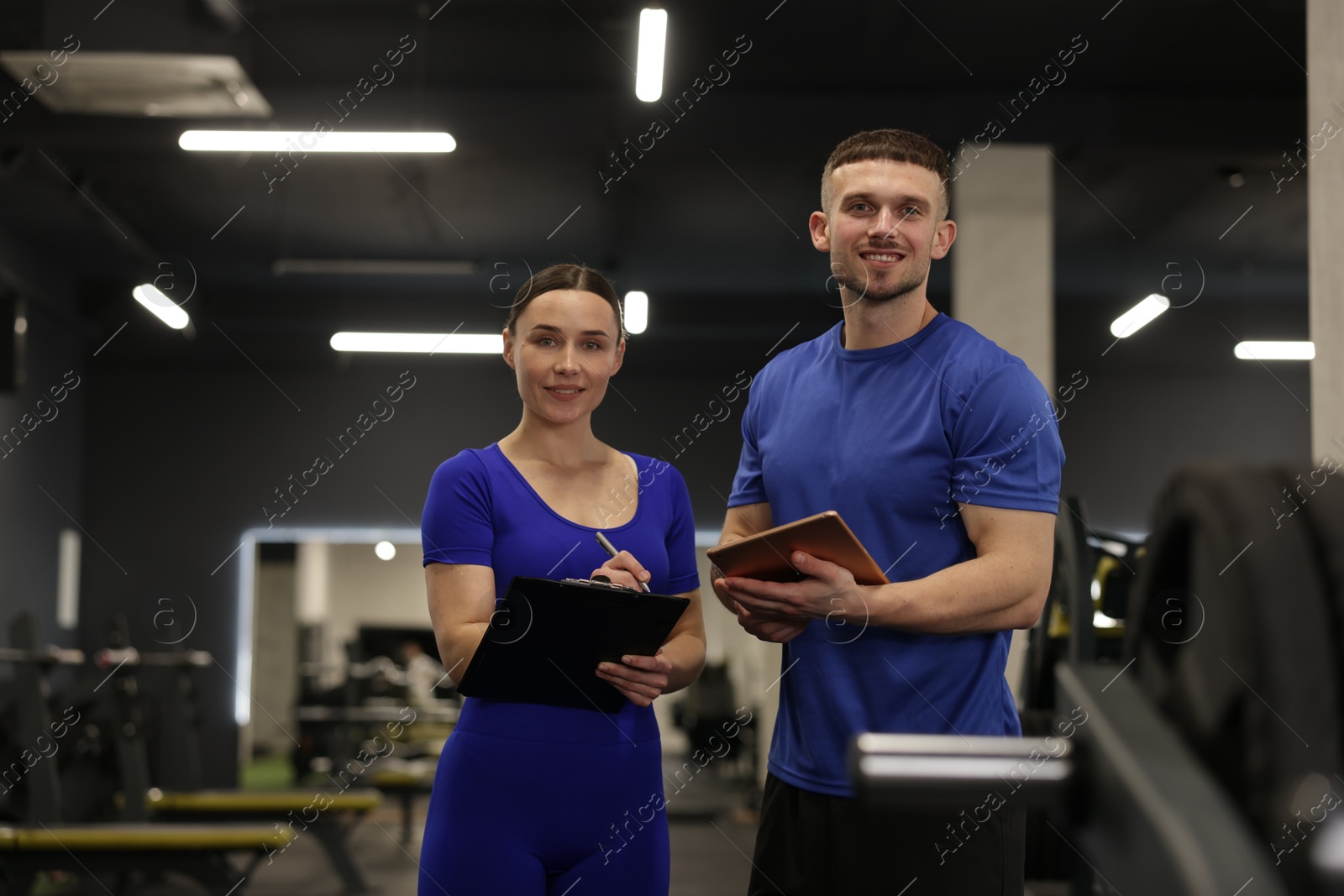 Photo of Personal trainers with clipboard and tablet in gym