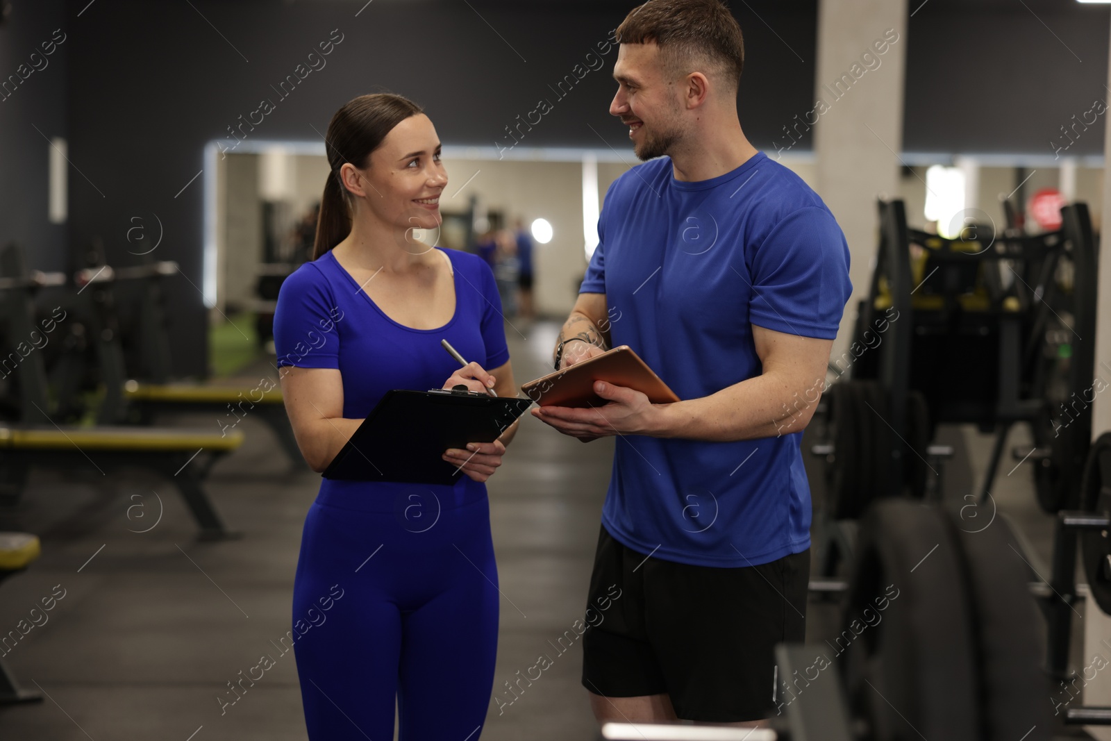 Photo of Personal trainers with clipboard and tablet in gym