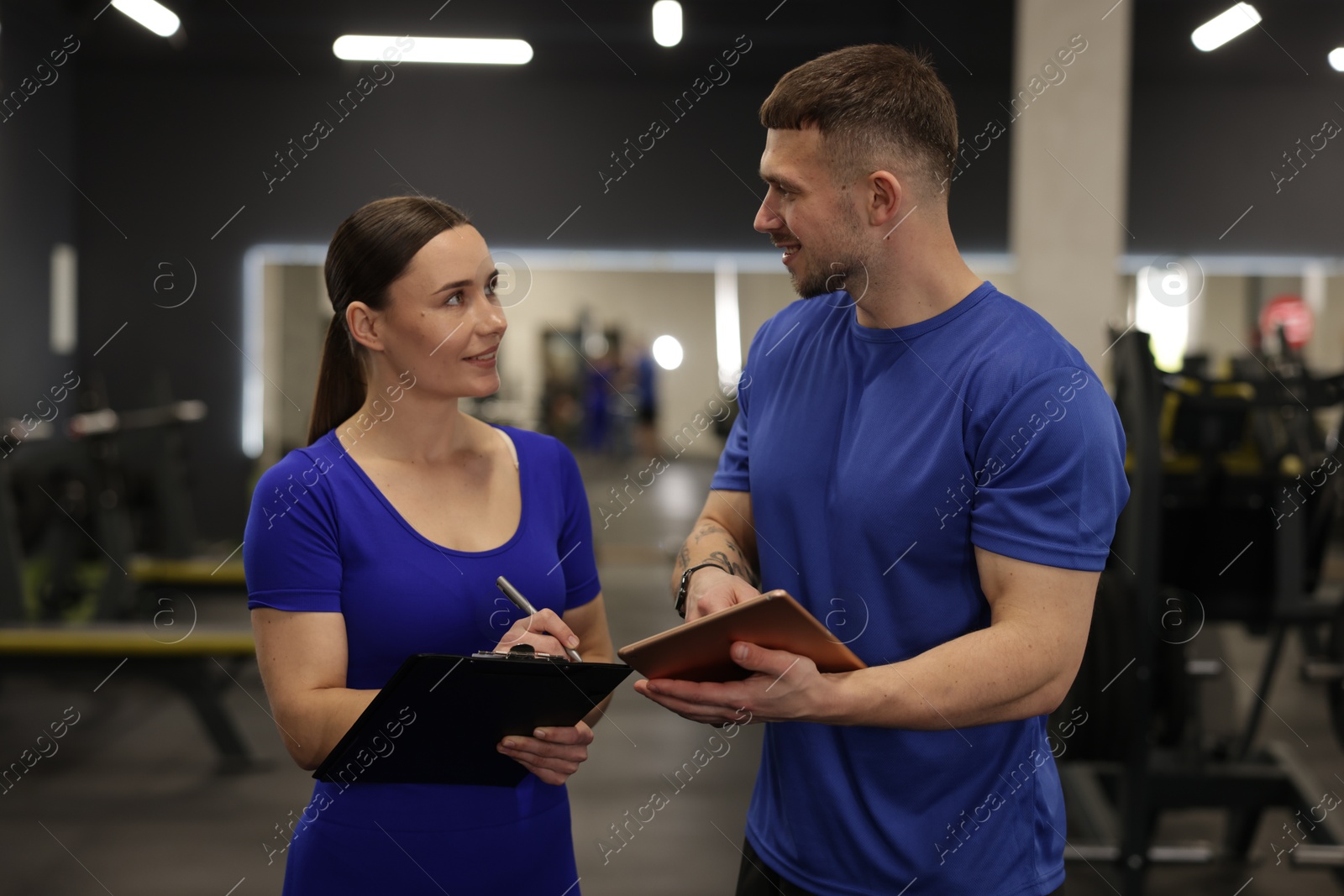 Photo of Personal trainers with clipboard and tablet in gym