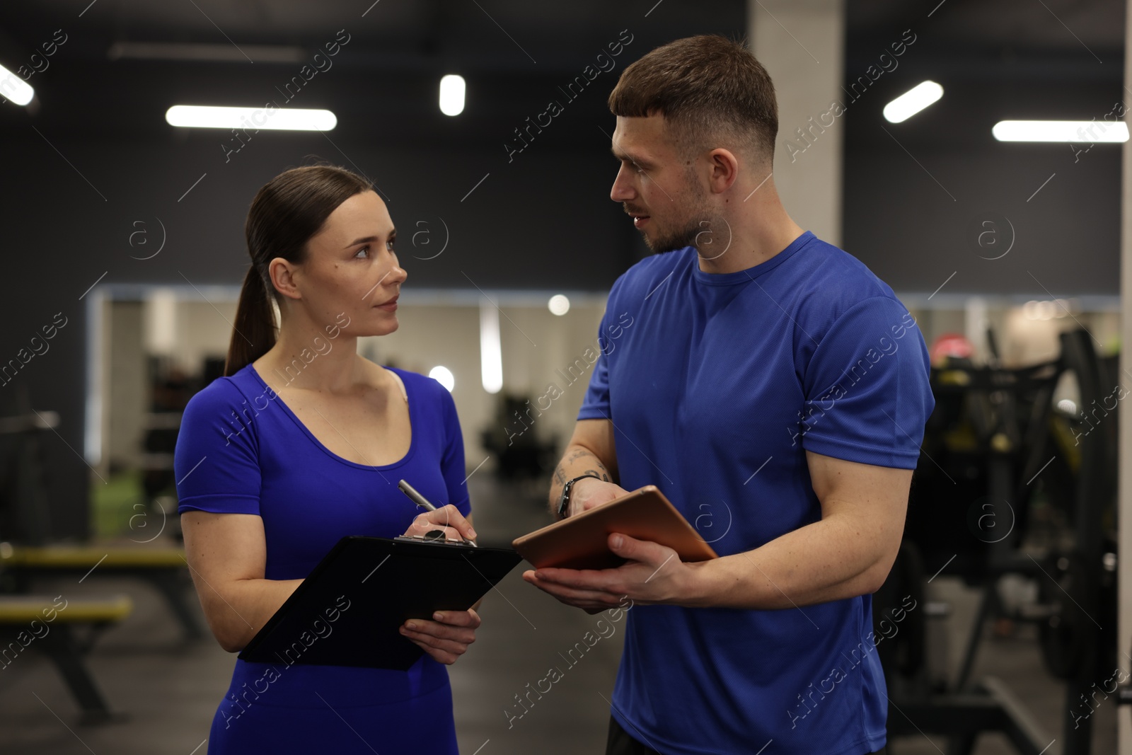 Photo of Personal trainers with clipboard and tablet in gym