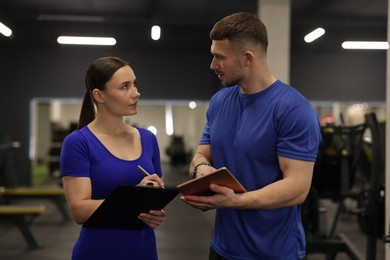 Photo of Personal trainers with clipboard and tablet in gym