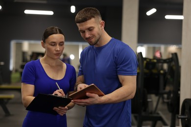 Photo of Personal trainers with clipboard and tablet in gym