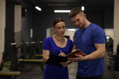 Photo of Personal trainers with clipboard and tablet in gym. Space for text