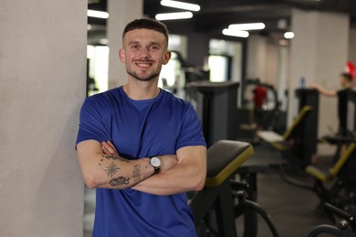 Photo of Portrait of professional personal trainer in gym. Space for text